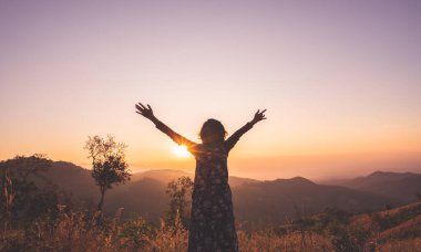 Gün doğumunda ellerini neşe ve ilhamla açan kadın..