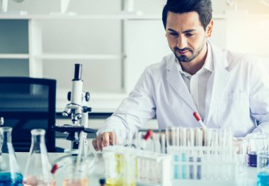Laboratuvar araştırması için elinde test tüpleri tutan bir bilim adamı.
