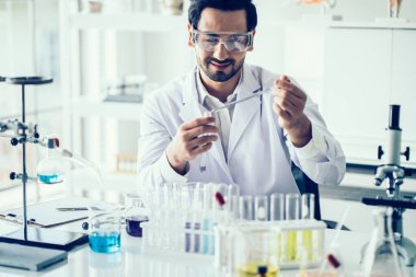 Laboratuvar araştırması için elinde test tüpleri tutan bir bilim adamı.