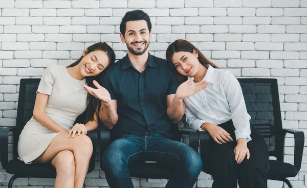 Aşk üçgeni, iki genç kadınla birlikte kanepede oturan neşeli gülen adam, arkadaşlık, çok eşlilik kavramı..
