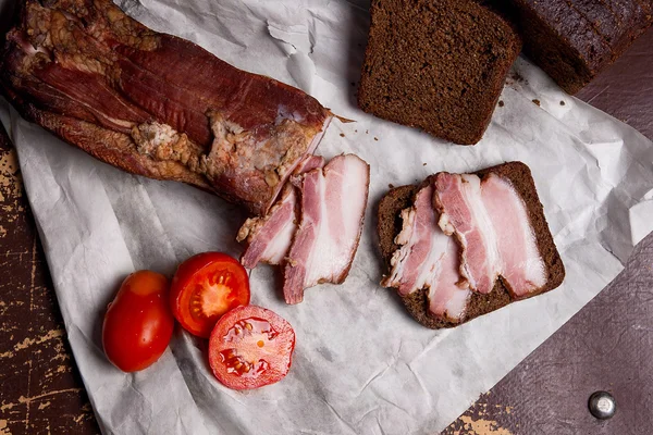 Gerookt spek met zwarte roggebrood en tomaten op de verpakking — Stockfoto