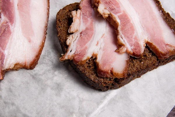 Close up view slices of smoked bacon with rye black bread on the