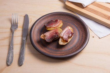 Ahşap zemin üzerine pastırma dilimlerini fırında patates.