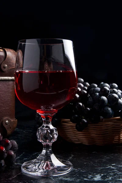 Copa de vino tinto sobre fondo de mármol oscuro. Racimo de gra azul — Foto de Stock