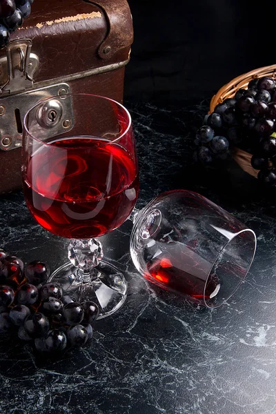 Copa de vino tinto sobre fondo de mármol oscuro. Racimo de gra azul — Foto de Stock