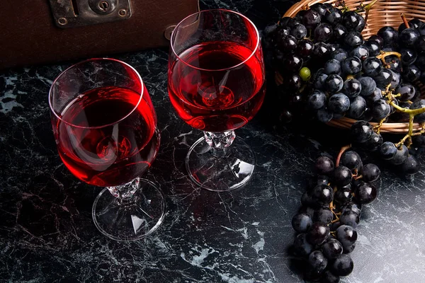 Copa de vino tinto sobre fondo de mármol oscuro. Racimo de gra azul — Foto de Stock