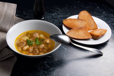 Metal kaşık, whit birkaç tost ile beyaz tabak fasulye çorbası