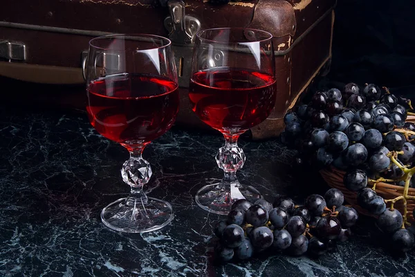 Copa de vino tinto sobre fondo de mármol oscuro. Racimo de gra azul — Foto de Stock