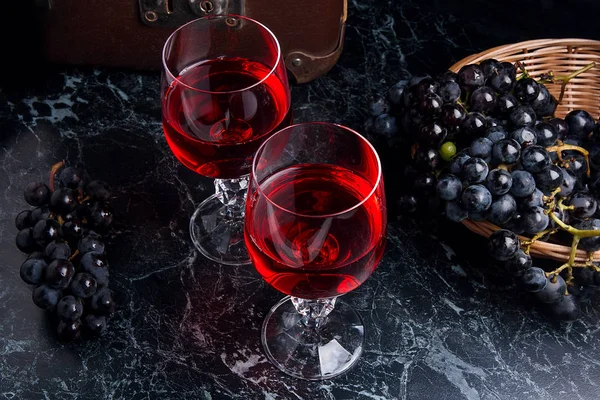 Copa de vino tinto sobre fondo de mármol oscuro. Racimo de gra azul — Foto de Stock