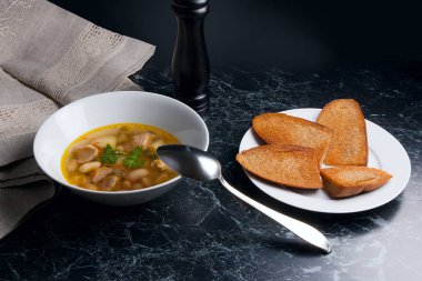 Metal kaşık, whit birkaç tost ile beyaz tabak fasulye çorbası