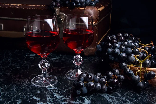 Copa de vino tinto sobre fondo de mármol oscuro. Racimo de gra azul — Foto de Stock