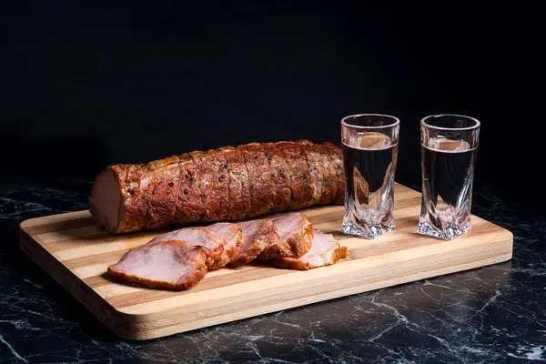 Shot glazen met wodka en plakjes gerookte vlees op houten cutt — Stockfoto