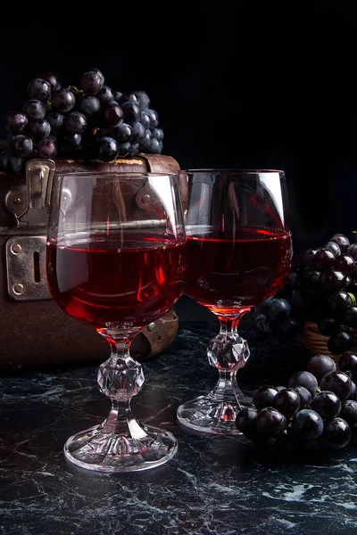 Copa de vino tinto sobre fondo de mármol oscuro. Racimo de gra azul — Foto de Stock