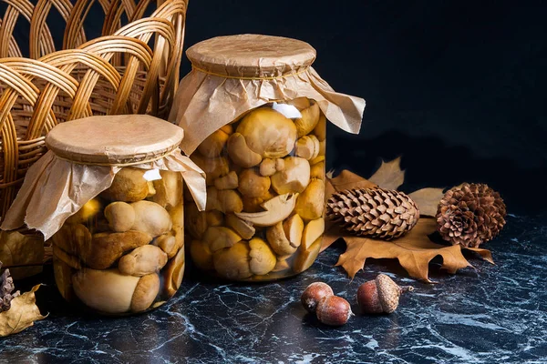 Two glass jars with wild marinated mushrooms on black marble bac — Stock Photo, Image