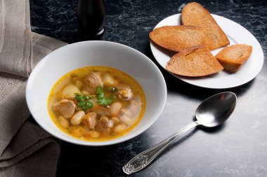 Metal kaşık, whit birkaç tost ile beyaz tabak fasulye çorbası