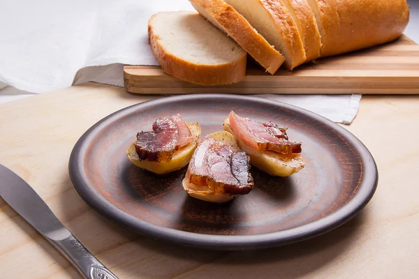 Baked potatoes with slices of bacon on wooden background. Slices