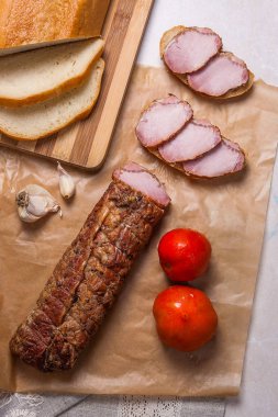 Füme dilimleri et ya da jambon kahverengi ambalaj kağıt üzerinde. Domates, garl
