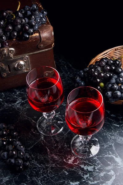 Copa de vino tinto sobre fondo de mármol oscuro. Racimo de gra azul — Foto de Stock