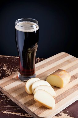 Cam kesme tahtası üzerinde füme peynir ile koyu bira ile.