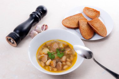 Metal kaşık, whit birkaç tost ile beyaz tabak fasulye çorbası