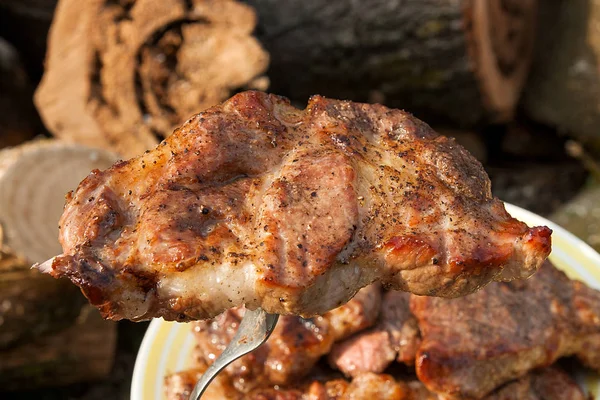 Vista da vicino della succosa bistecca di maiale sulla forchetta cotta a fiamma aperta — Foto Stock