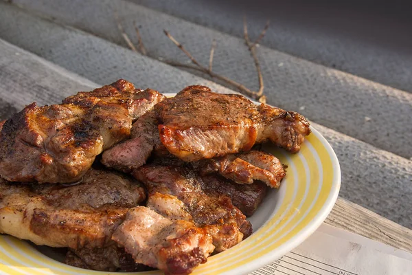 Succose bistecche di maiale cotte su una griglia a fiamma aperta su una grande pla bianca — Foto Stock