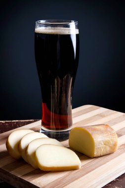 Cam kesme tahtası üzerinde füme peynir ile koyu bira ile.