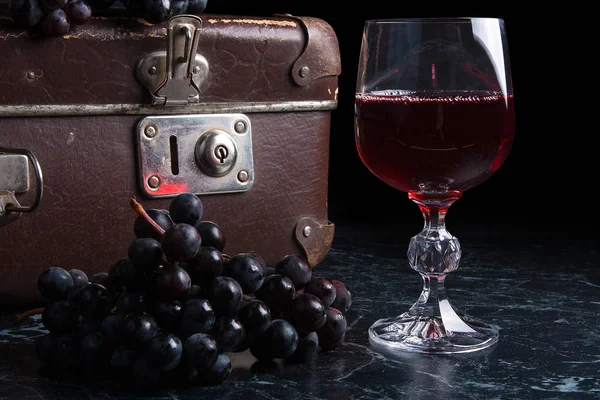 Copa de vino tinto sobre fondo de mármol oscuro. Racimo de gra azul — Foto de Stock