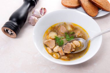 Metal kaşık, whit birkaç tost ile beyaz tabak fasulye çorbası