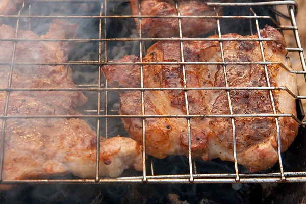 Vista de cerca de la jugosa carne de cerdo cocinada en una parrilla de llama abierta — Foto de Stock