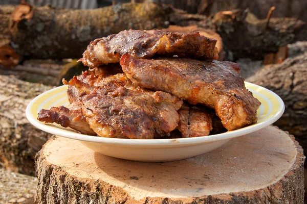 Juicy pork steaks cooked on an open flame grill on big white pla — Stock Photo, Image