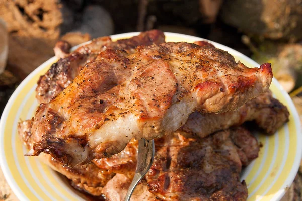 Vista da vicino della succosa bistecca di maiale sulla forchetta cotta a fiamma aperta — Foto Stock