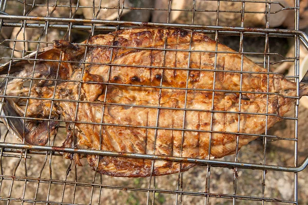 Fresh fish with sauce cooked on an open flame grill.