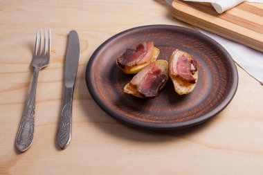 Ahşap zemin üzerine pastırma dilimlerini fırında patates.