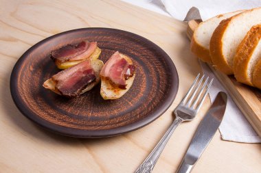 Ahşap zemin üzerine pastırma dilimlerini fırında patates. Dilimleri