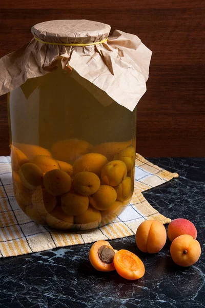 Juicy harvested apricots and big glass jar with canned apricot c — Stock Photo, Image