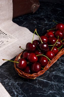 Karanlık mermer geri üzerinde sarı ahşap sepet içinde taze organik kiraz