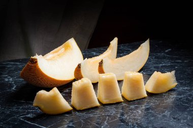 Yarım ve dilimlenmiş honeydew kavun meyve karanlık mermer arka plan üzerinde