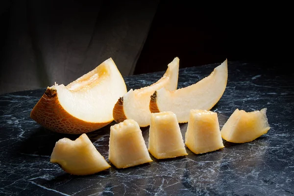 Yarım ve dilimlenmiş honeydew kavun meyve karanlık mermer arka plan üzerinde