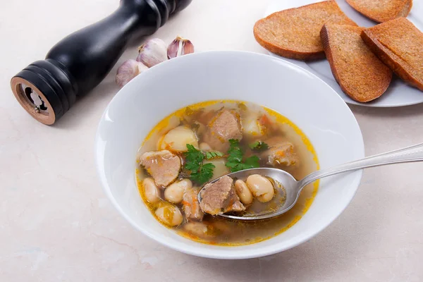 Metal kaşık, whit birkaç tost ile beyaz tabak fasulye çorbası