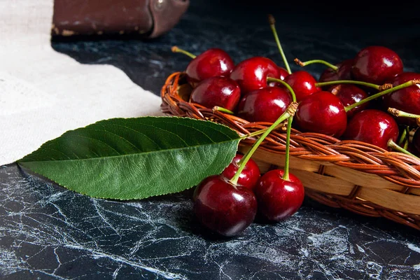Several red sweet cherries and big green leaf on the table. Fres