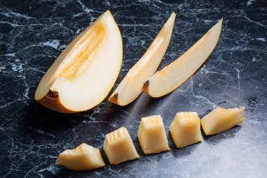 Yarım ve dilimlenmiş honeydew kavun meyve karanlık mermer arka plan üzerinde
