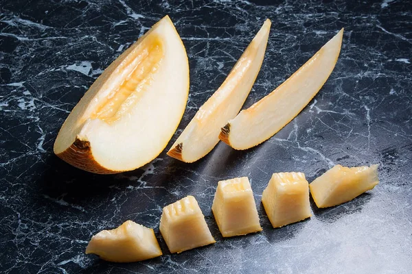 Yarım ve dilimlenmiş honeydew kavun meyve karanlık mermer arka plan üzerinde