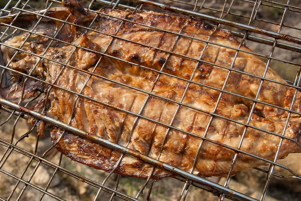 Fresh fish with sauce cooked on an open flame grill.
