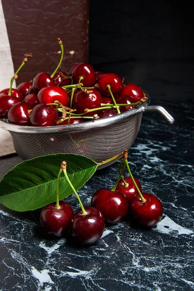 Several red sweet cherries and big green leaf on the table. Fres