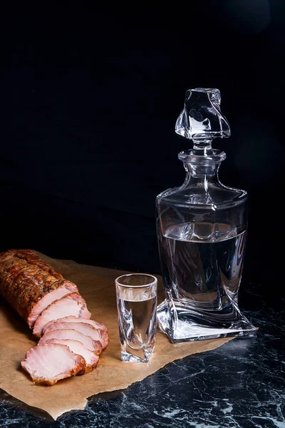 Fles en shot glazen met wodka met plakjes gerookte vlees op — Stockfoto