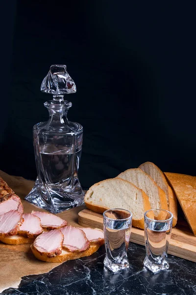 Fles en shot glas met wodka met plakjes gerookte vlees op b — Stockfoto