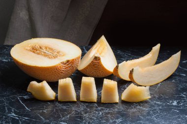 Yarım ve dilimlenmiş honeydew kavun meyve karanlık mermer arka plan üzerinde