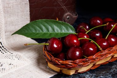 Taze organik kiraz ve büyük yaprak yeşil sarı ahşap sepeti 