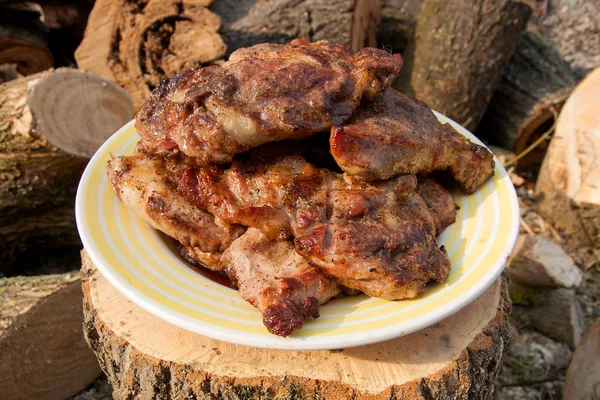 Succose bistecche di maiale cotte su una griglia a fiamma aperta su una grande pla bianca — Foto Stock